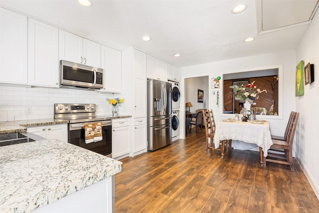 6401 Deihl Rd Unit 1401, Houston, TX 77092 - kitchen with appliances with stainless steel finishes, estacked washer and dryer, dark wood finished floors, white cabinetry, and recessed lighting