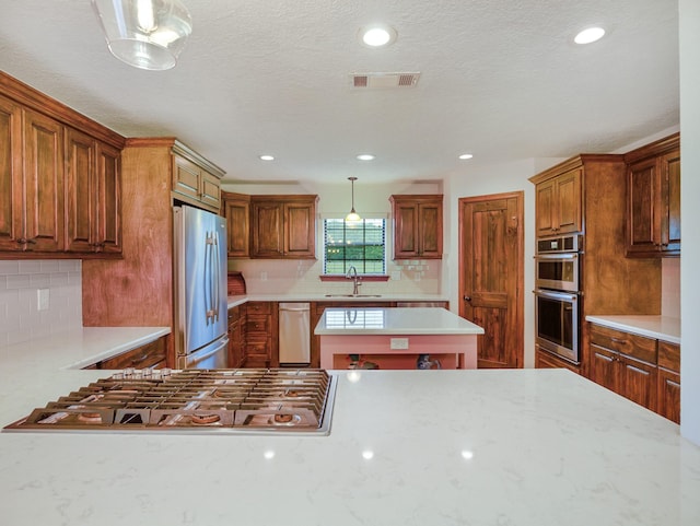 413 Christensen Rd, Hankamer, TX 77560 - kitchen featuring stainless steel appliances, backsplash, decorative light fixtures, recessed lighting, and brown cabinetry