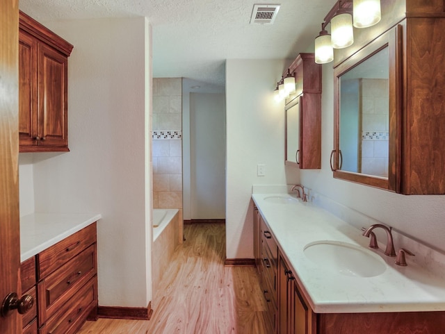 413 Christensen Rd, Hankamer, TX 77560 - full bath with wood finished floors, double vanity, a bathtub, and a textured ceiling