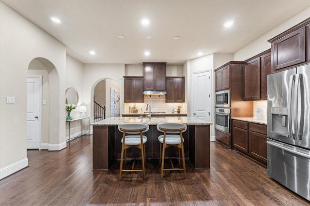 13207 Parkway Meadows Dr, Houston, TX 77077 - kitchen with appliances with stainless steel finishes, backsplash, dark wood-style floors, dark brown cabinetry, and arched walkways