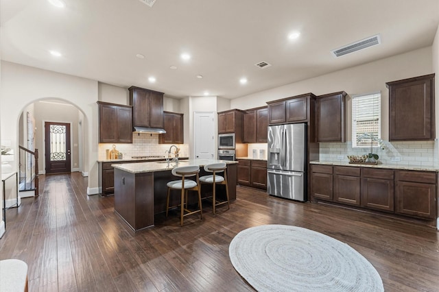 13207 Parkway Meadows Dr, Houston, TX 77077 - kitchen featuring appliances with stainless steel finishes, arched walkways, dark brown cabinets, decorative backsplash, and recessed lighting