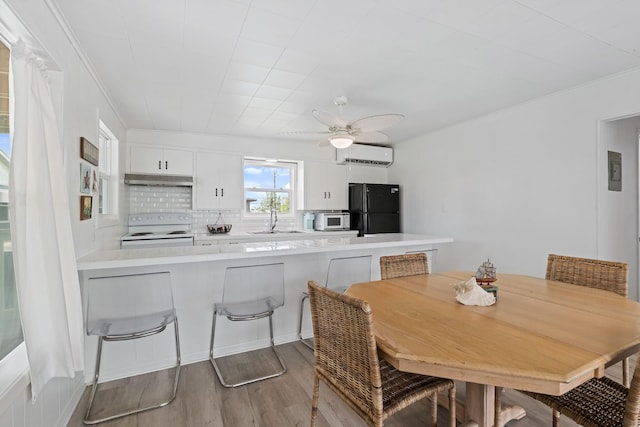 106 E Madison Ave, Port O Connor, TX 77982 - dining space featuring an AC wall unit, wood finished floors, a ceiling fan, and crown molding