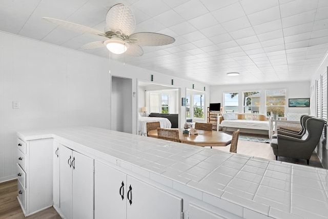 106 E Madison Ave, Port O Connor, TX 77982 - kitchen with open floor plan, tile countertops, wood finished floors, white cabinets, and a ceiling fan