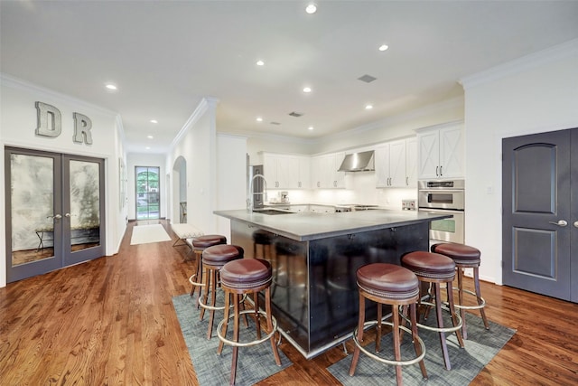 4004 Childress St, Houston, TX 77005 - kitchen featuring appliances with stainless steel finishes, wall chimney exhaust hood, ornamental molding, dark wood-style floors, and french doors