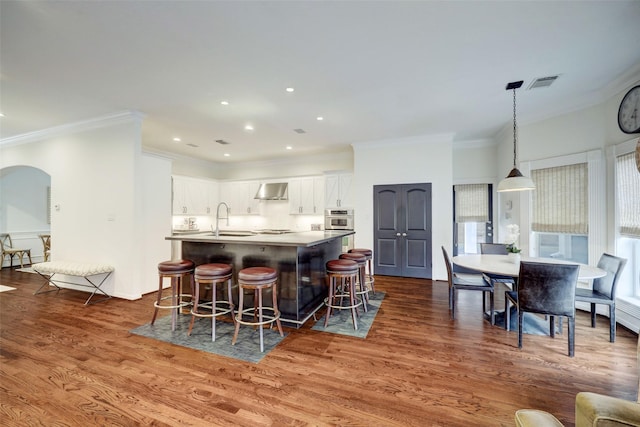 4004 Childress St, Houston, TX 77005 - kitchen with oven, dark wood finished floors, a kitchen island with sink, white cabinetry, and a kitchen breakfast bar