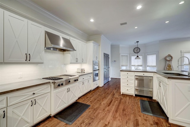 4004 Childress St, Houston, TX 77005 - kitchen featuring wall chimney exhaust hood, appliances with stainless steel finishes, tasteful backsplash, crown molding, and white cabinetry
