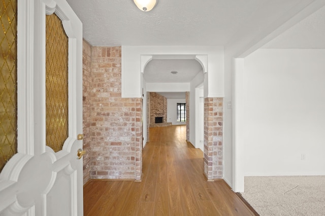 2531 Anzalone Dr, Spring, TX 77373 - hall with brick wall, light wood-style flooring, and a textured ceiling