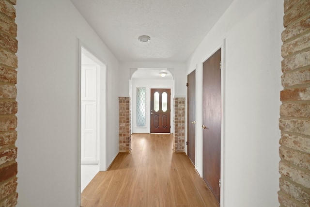 2531 Anzalone Dr, Spring, TX 77373 - hall featuring light wood finished floors, a textured ceiling, and brick wall