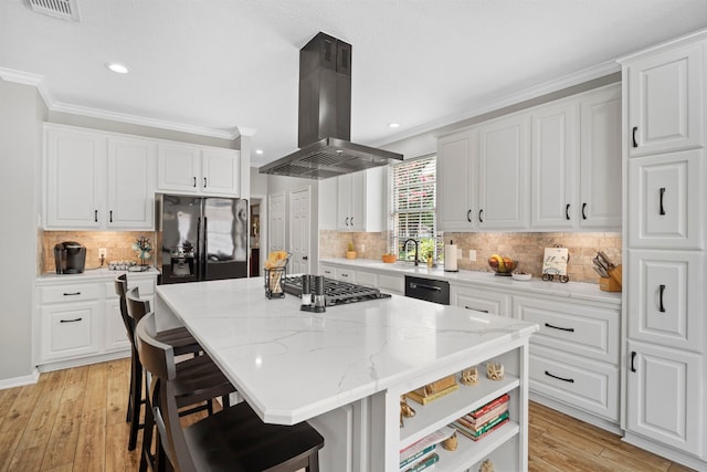 8522 Hillsboro Pl, Sugar Land, TX 77479 - kitchen featuring island range hood, black refrigerator with ice dispenser, stainless steel gas stovetop, a kitchen island, and a kitchen bar