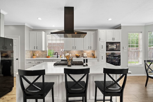 8522 Hillsboro Pl, Sugar Land, TX 77479 - kitchen with black appliances, island range hood, light wood-style floors, backsplash, and crown molding