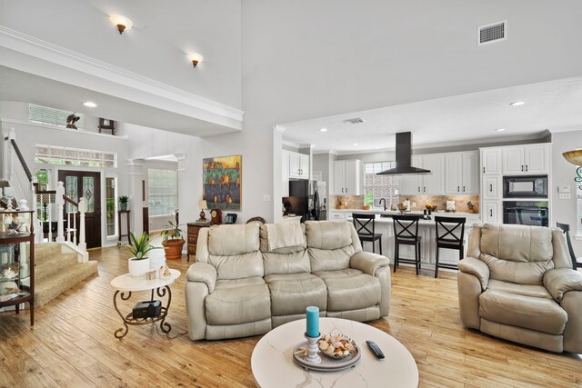 8522 Hillsboro Pl, Sugar Land, TX 77479 - living room featuring light wood-style flooring, recessed lighting, ornamental molding, and a high ceiling