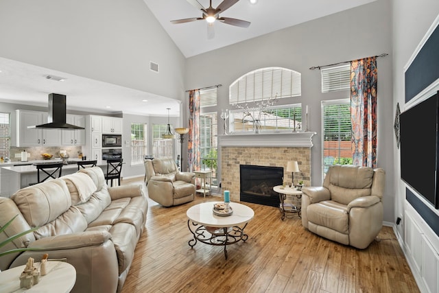 8522 Hillsboro Pl, Sugar Land, TX 77479 - living room featuring high vaulted ceiling, ceiling fan, a brick fireplace, and light wood-type flooring