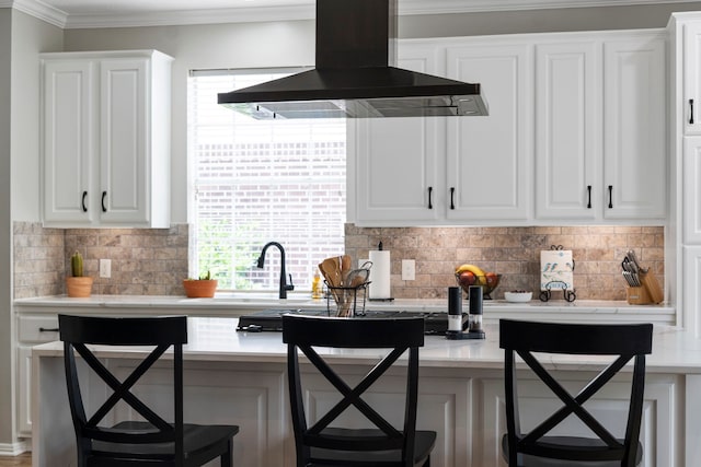8522 Hillsboro Pl, Sugar Land, TX 77479 - kitchen with wall chimney range hood, backsplash, white cabinets, light countertops, and ornamental molding