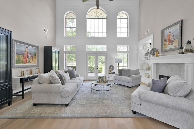 15203 Wildwood Cir, Magnolia, TX 77354 - living room featuring a towering ceiling, built in features, wood finished floors, ceiling fan, and a high end fireplace