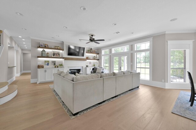 15203 Wildwood Cir, Magnolia, TX 77354 - living area featuring ornamental molding, a ceiling fan, light wood-style floors, a glass covered fireplace, and plenty of natural light