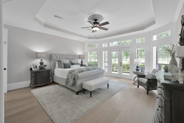 15203 Wildwood Cir, Magnolia, TX 77354 - bedroom with a raised ceiling, multiple windows, french doors, and light wood finished floors