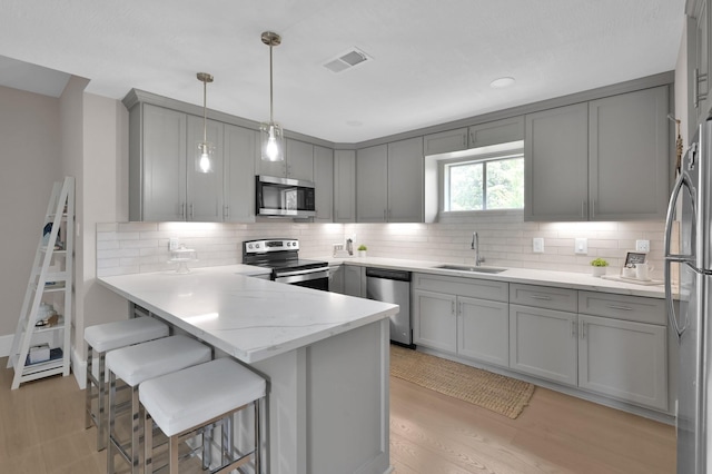 15203 Wildwood Cir, Magnolia, TX 77354 - kitchen featuring stainless steel appliances, gray cabinetry, a peninsula, and tasteful backsplash