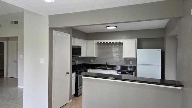 3018 Sherborne St, Pearland, TX 77584 - kitchen with appliances with stainless steel finishes, dark countertops, light tile patterned flooring, white cabinetry, and tasteful backsplash