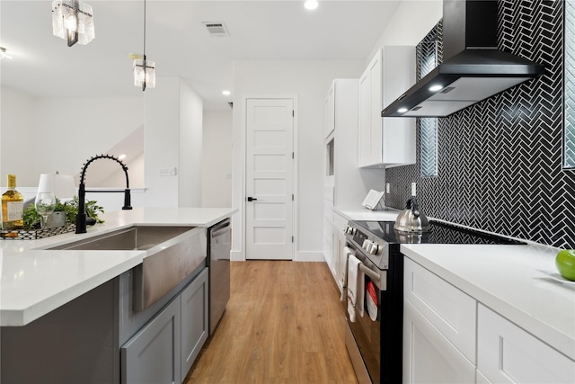 3022 Drew St, Houston, TX 77004 - kitchen featuring stainless steel appliances, wall chimney range hood, backsplash, light wood finished floors, and light countertops