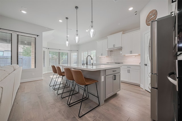 30706 Southern Dewberry Ct, Fulshear, TX 77441 - kitchen with freestanding refrigerator, a kitchen bar, under cabinet range hood, light countertops, and decorative backsplash