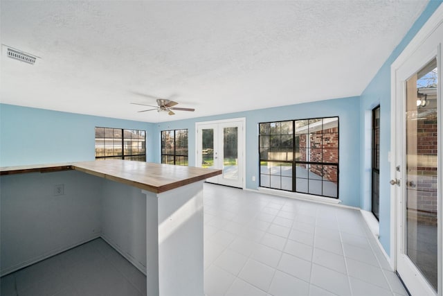 12417 Pegasus Dr, Willis, TX 77318 - kitchen with french doors, wooden counters, a textured ceiling, a ceiling fan, and light tile patterned flooring