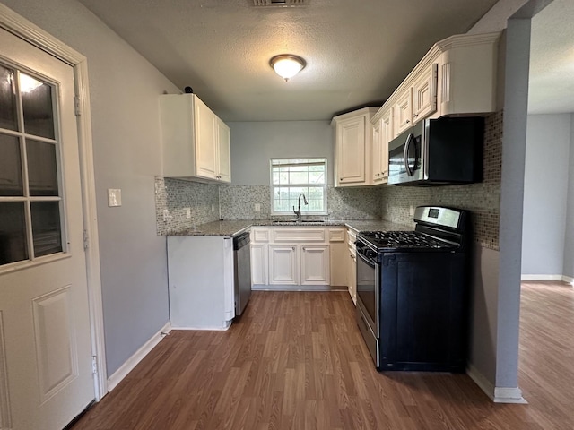1826 Wayside Dr, Texas City, TX 77590 - kitchen featuring stainless steel appliances, dark wood-type flooring, decorative backsplash, white cabinetry, and a textured ceiling