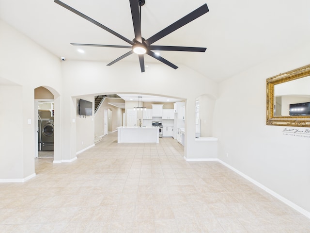 16911 Wortley Dr, Houston, TX 77084 - unfurnished living room featuring washer / dryer, arched walkways, ceiling fan, lofted ceiling, and light tile patterned flooring