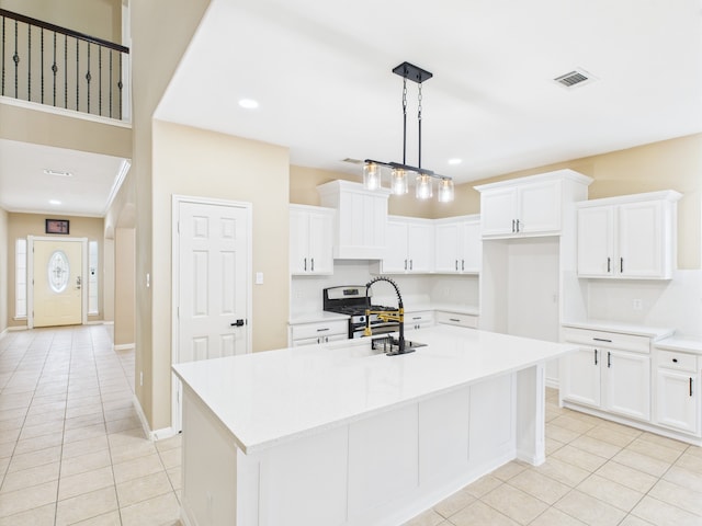 16911 Wortley Dr, Houston, TX 77084 - kitchen with stainless steel gas stove, light tile patterned flooring, a center island with sink, light countertops, and white cabinets