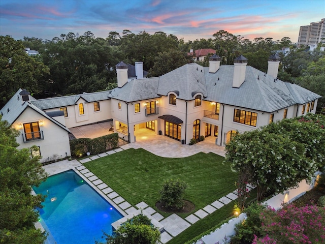 1039 Kirby Dr, Houston, TX 77019 - back of house at dusk featuring a chimney, a patio area, stucco siding, and a balcony
