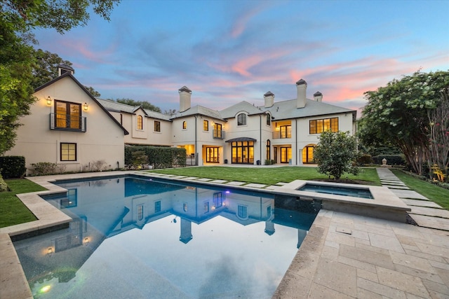 1039 Kirby Dr, Houston, TX 77019 - back of house at dusk featuring a lawn, a chimney, a patio, and stucco siding