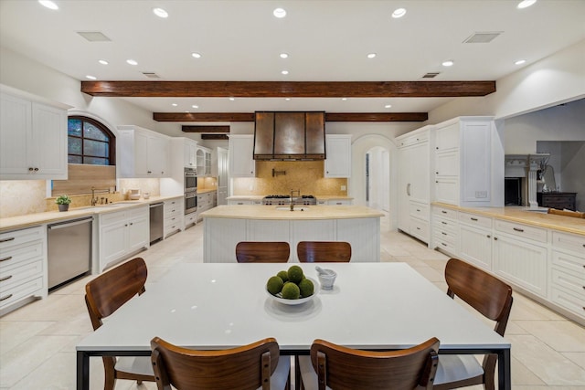 1039 Kirby Dr, Houston, TX 77019 - kitchen featuring appliances with stainless steel finishes, custom exhaust hood, recessed lighting, decorative backsplash, and beamed ceiling