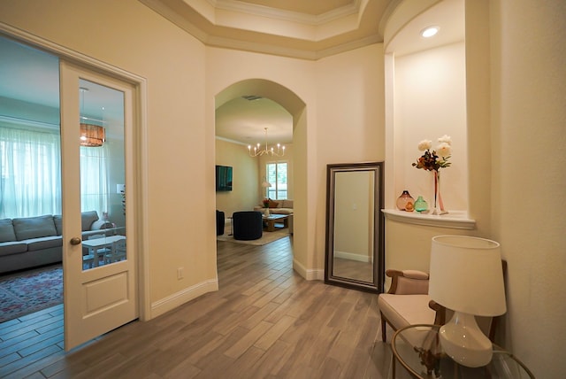 13114 Sierra National Dr, Humble, TX 77346 - hallway featuring crown molding, wood finished floors, arched walkways, a chandelier, and a raised ceiling