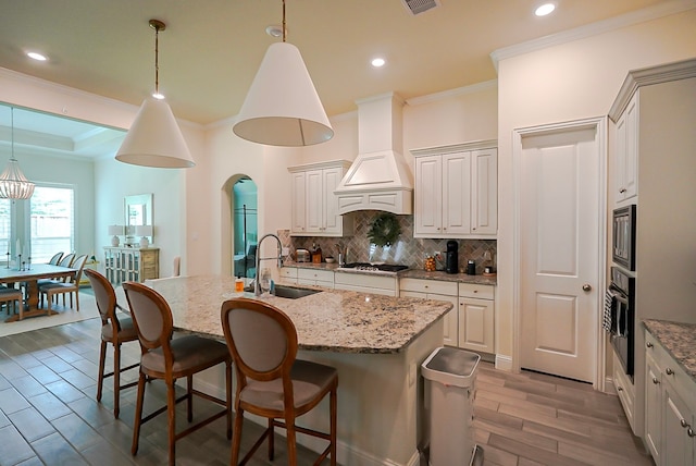 13114 Sierra National Dr, Humble, TX 77346 - kitchen with appliances with stainless steel finishes, crown molding, backsplash, light wood-style floors, and a center island with sink