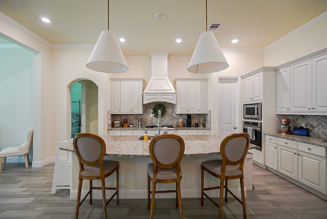 13114 Sierra National Dr, Humble, TX 77346 - kitchen with stainless steel appliances, decorative backsplash, ornamental molding, custom range hood, and wood finished floors