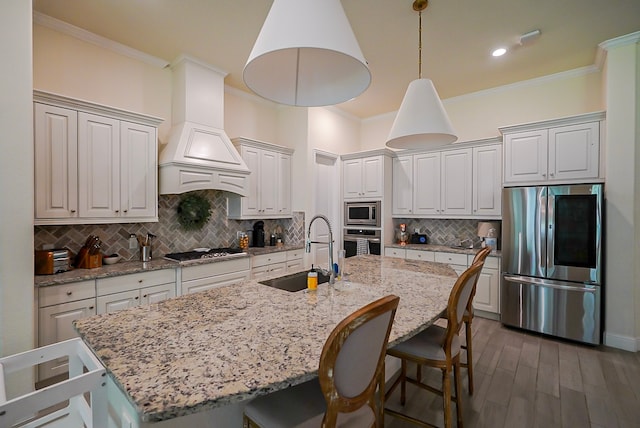 13114 Sierra National Dr, Humble, TX 77346 - kitchen featuring appliances with stainless steel finishes, custom exhaust hood, ornamental molding, a kitchen breakfast bar, and a center island with sink
