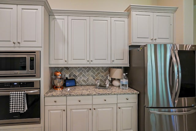 13114 Sierra National Dr, Humble, TX 77346 - kitchen with stainless steel appliances, tasteful backsplash, light stone countertops, and white cabinets