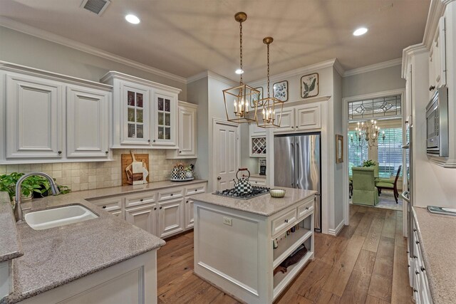 11 E Thymewood Pl, The Woodlands, TX 77382 - kitchen featuring a chandelier, appliances with stainless steel finishes, crown molding, decorative backsplash, and hardwood / wood-style floors