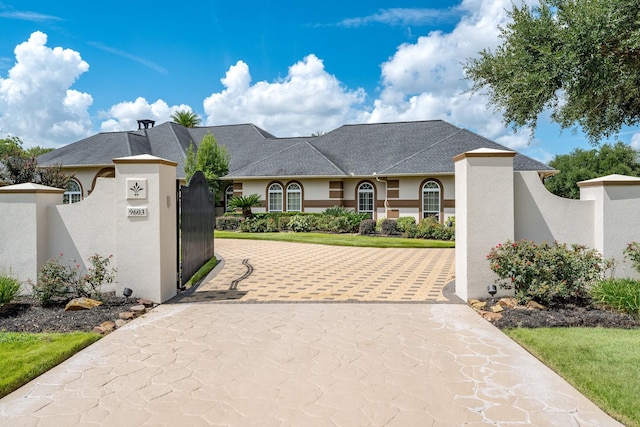 9603 Stonebridge Pl, Tomball, TX 77375 - view of front of home featuring stucco siding, a gate, a fenced front yard, driveway, and a shingled roof