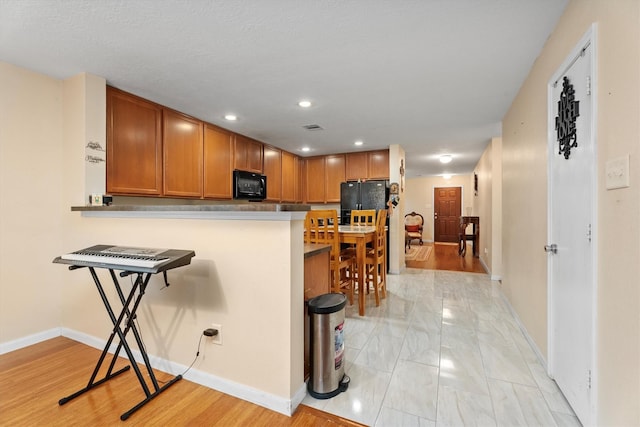 16307 Melody View Ct, Cypress, TX 77429 - kitchen featuring black appliances, a breakfast bar area, recessed lighting, brown cabinetry, and light marble finish flooring