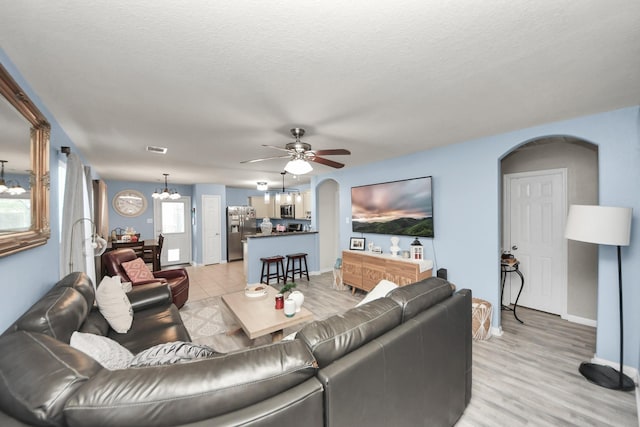 28961 San Bernard River Loop, Spring, TX 77386 - living room featuring arched walkways, a chandelier, ceiling fan, and light wood finished floors