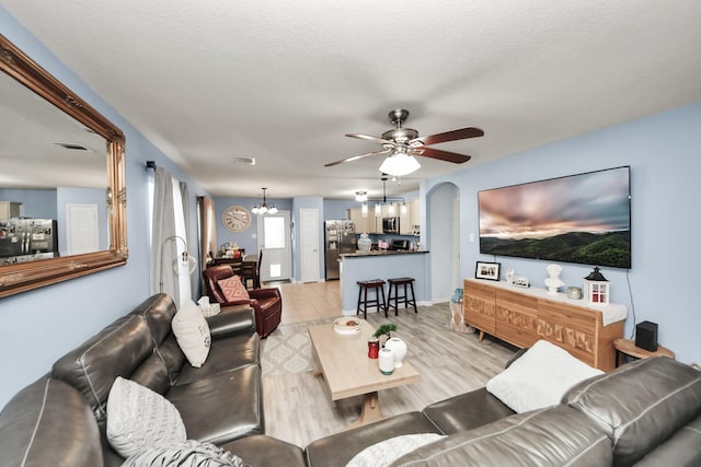 28961 San Bernard River Loop, Spring, TX 77386 - living room with a chandelier, ceiling fan, arched walkways, and light wood-type flooring