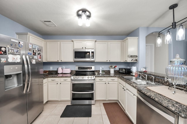 28961 San Bernard River Loop, Spring, TX 77386 - kitchen with stainless steel appliances, light tile patterned floors, hanging light fixtures, and dark stone countertops