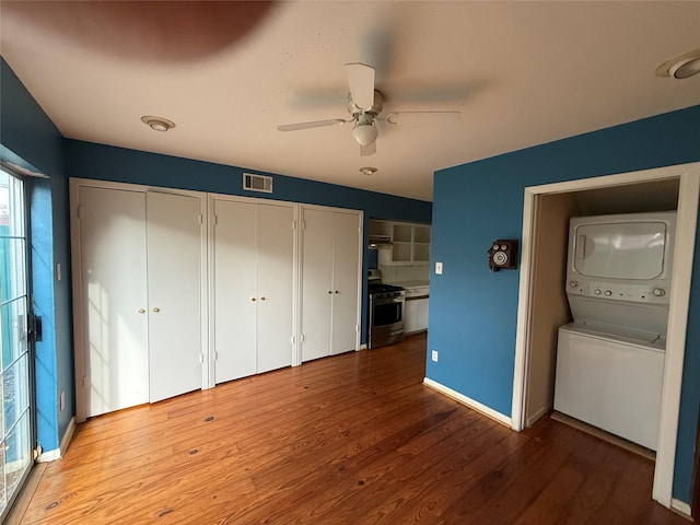 1226 W Drew St Unit B, Houston, TX 77006 - unfurnished bedroom with stacked washer / dryer, two closets, wood finished floors, and a ceiling fan