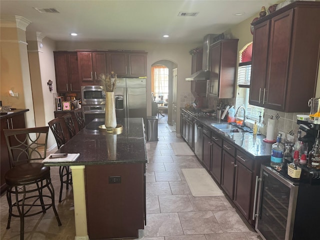 4714 Loggia Ln, Humble, TX 77396 - kitchen with beverage cooler, arched walkways, a center island, stainless steel appliances, and a kitchen bar