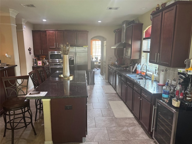 4714 Loggia Ln, Humble, TX 77396 - kitchen featuring wine cooler, arched walkways, a kitchen island, a breakfast bar, and dark stone countertops