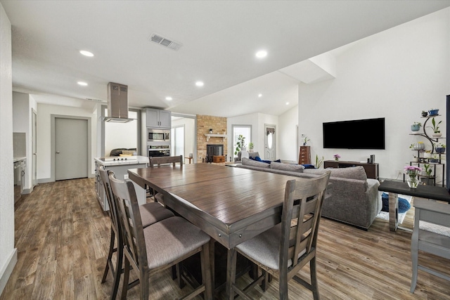 8218 Waynemer Way, Houston, TX 77040 - dining room with wood finished floors, vaulted ceiling, recessed lighting, and a fireplace