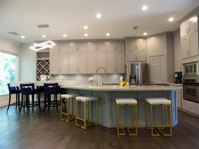 12636 Briar Patch Rd, Houston, TX 77077 - kitchen featuring stainless steel appliances, decorative backsplash, a breakfast bar area, dark wood-style flooring, and recessed lighting