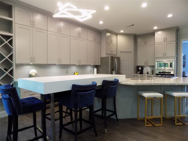 12636 Briar Patch Rd, Houston, TX 77077 - kitchen with stainless steel appliances, decorative backsplash, dark wood finished floors, a kitchen bar, and recessed lighting