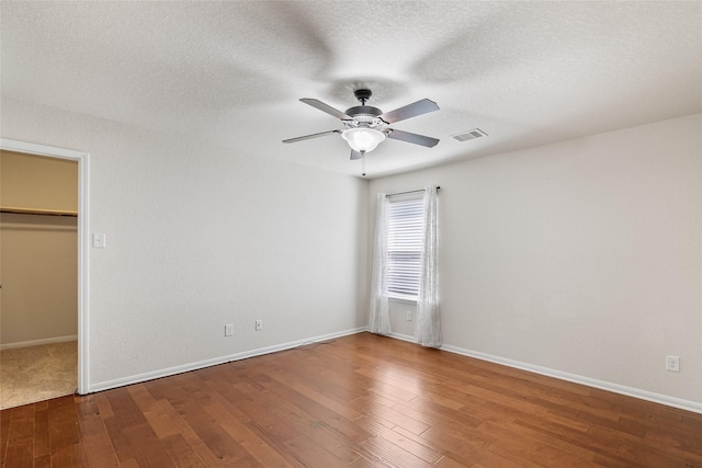 15218 Zenith Glen Ln, Cypress, TX 77429 - unfurnished bedroom featuring wood finished floors, a walk in closet, ceiling fan, a closet, and a textured ceiling