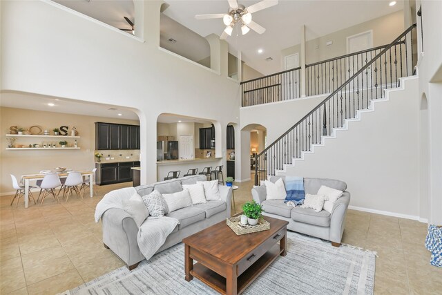 19538 Salt Grass Meadow Dr, Cypress, TX 77433 - living room with arched walkways, ceiling fan, light tile patterned floors, stairway, and a high ceiling